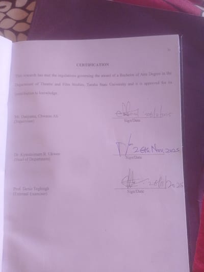 The image shows a page from a document, likely a thesis or dissertation, with the title "CERTIFICATION" at the top. It appears to be a formal document, as indicated by the typed text and signatures. The text states that the research has met the regulations for the award of a Bachelor of Arts Degree in the Department of Theatre and Film Studies, Taraba State University, and is approved for its contribution to knowledge.

Below the main text, there are three sections for signatures and dates, each preceded by a name and designation.

The first section is for "Mr. Danjuma, Chwanu Ali (Supervisor)". There is a signature and the date "26/11/2025" written in purple ink.

The second section is for "Dr. Kyantirimam R. Ukwen (Head of Department)". There is a signature and the date "26th Nov, 2025" written in purple ink.

The third section is for "Prof. Denis Teghtegh (External Examiner)". There is a signature and the date "26/11/2025" written in purple ink.

The document is a light purple color, suggesting it might be printed on colored paper. The overall lighting in the image is soft, and the focus is on the document itself. The background appears to be a darker, textured surface, possibly a table or cover. There are no visible environmental details that would indicate the specific location within Magajin Gari, Nigeria, other than the mention of Taraba State University.