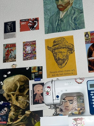 The image is a collage of stickers and images attached to a white surface. There's a reproduction of Van Gogh’s portrait, a yellow image with the text "People often make art, but do not notice it," and various pop culture references, including a "Joker" comic book cover and a "Yoshitomo Nara" print. A sewing machine with Hello Kitty stickers is also visible, as is a skull painting. The overall aesthetic is cluttered, youthful, and artistic.