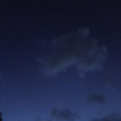 The image shows a night sky with scattered clouds. The sky is a deep blue, transitioning to a lighter shade towards the bottom of the frame. The clouds are various shades of gray and appear to be thinly spread. The image could plausibly be taken from Ihururu, Kenya, but without additional context or information, it's not possible to confirm the exact location.