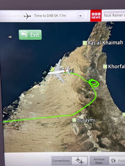 A screen displays an airplane's flight path on a map. The plane, located near Dubai (labeled "Dai"), has a green-traced route indicating a loop towards Khorfakan and then a straight path towards Buraymi. Other labeled locations include Ras al Khaimah. The screen also displays "Time to DXB 0h 17m" (estimated time to Dubai is 17 minutes). The BBC News logo and "Nick Reiner c" are visible. Interface buttons for "Exit," "Connections," "Airshow Maps," and "Explore" are also displayed.