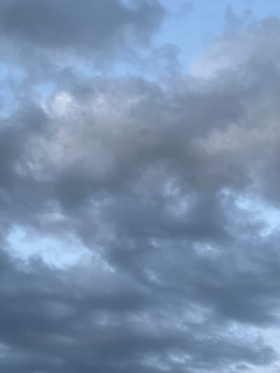 The media file captures a low-angle view of a cloudy sky. The clouds are dark and heavy, suggesting overcast or stormy weather. Patches of lighter sky are visible through breaks in the clouds, indicating daylight. The overall impression is one of a dramatic and somewhat somber sky, possibly before or during rain. There are no people, objects, or text visible in the image, only the natural phenomenon of clouds against the sky. The setting is outdoors, with the focus exclusively on the atmospheric conditions.