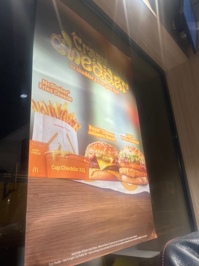 This is a McDonald's advertisement featuring a variety of cheddar-themed menu items. The ad highlights "Crazy Cheddar," with items like McShaker Fries Cheese, Royal Cheesy Jalapeño Bacon, CBO Extra Cheddar, and Cup Cheddar XXL. The text "Du cheddar à n'en plus finir" suggests an abundance of cheddar in these offerings. There's also a disclaimer that the McShaker Fries Cheese promotion is for a limited time, emphasizing the cheese-based sauce and fries experience. The ad promotes a cheesy and indulgent McDonald's experience.