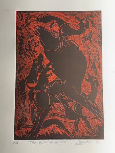 The image is a linocut print, predominantly black figures on a vibrant red-orange etched background. It depicts a chaotic scene titled "Toro luchando con perros" (Bull fighting with dogs), signed "Amorcery" and dated '89, with "P/A" indicating an artist's proof. This artwork evokes the traditional cultural practice of bullfighting, relevant to cities like Ronda, Spain, known for its bullfighting heritage.

In the center, a large, dark-silhouetted bull is positioned, facing upwards and left, appearing distressed or in mid-action with a stylized eye visible. Surrounding the bull are at least six smaller, dark-silhouetted dogs in dynamic poses of barking, running, and lunging. A small, stylized bird-like figure with wings is perched on the bull's upper back near its neck. In the background, on both the left and right sides, numerous slender, stylized human figures are rendered in dark silhouette against the red-orange etched lines. Many of these figures have raised arms, suggesting movement, participation, or observation. The entire background is filled with dense, radiating red-orange lines and patterns, creating an energetic and intense atmosphere, including a prominent sun-like or starburst motif in the upper left corner. The composition relies on stark contrast between the solid black forms and the intricate red-orange linework.