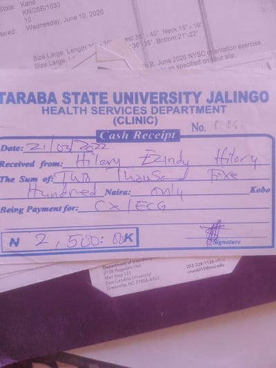 The image is a close-up of a cash receipt from the Taraba State University Health Services Department (Clinic) in Jalingo, Nigeria. The receipt is filled out in blue ink. The date is recorded as "21/03/2022". The amount received is "Two Thousand Five Hundred Naira" (N 2,500: 00K). The payment is for "CX/ECG". The receipt is signed by someone named "Hilary Ezindy". There is also a printed section at the bottom with details about the "Department of Interdisciplinary", "East Carolina University", and contact information including a phone number and email address. The background appears to be other papers, possibly related to clothing sizes and a NYSC orientation exercise. The lighting suggests it's indoors, and the overall tone is that of a completed transaction.