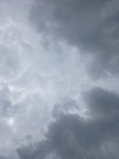 The media file shows a close-up, low-angle view of a cloudy sky. The clouds are dense and dark gray, with some lighter patches suggesting diffused sunlight. There are no people, objects, or discernible location cues in the image, making it a purely atmospheric scene. The weather appears to be overcast, possibly indicative of impending rain or a stormy condition, given the dark hue of the clouds. The time of day is not explicitly clear, but the overall lighting suggests it is daytime. The emotion evoked by the image is likely somber or dramatic due to the heavy cloud cover. There is no visible text in the media file. The context of Pavlovsky Posad, Russia, provides a geographical setting but is not visually represented within the image itself.
