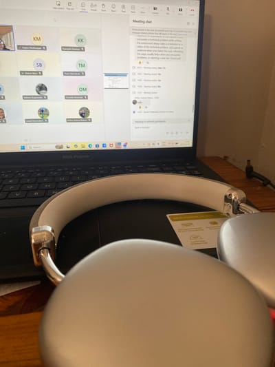 The image shows a laptop running a Microsoft Teams meeting in what appears to be an indoor setting. The laptop, an ASUS Vivobook, displays a meeting chat window. Several participants' names and profile icons are visible. The laptop's keyboard is also visible.
A pair of white headphones are positioned on the laptop, partially obscuring the keyboard and screen. The headphones have silver metal accents on the headband.
Based on the meeting participants' names and the laptop's local configuration, it is likely the image was captured in Pretoria, South Africa.