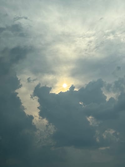 The image depicts a dramatic sky filled with clouds and the sun. The sun is partially obscured by dark, heavy clouds on the right side of the frame, creating a strong contrast with the brighter, more diffuse clouds on the left. The lighting suggests a time of day when the sun is either rising or setting, or perhaps a stormy afternoon. The clouds are textured and varied, with some appearing wispy and others thick and ominous. The overall scene evokes a sense of atmospheric power and perhaps a touch of foreboding or awe, depending on the viewer's interpretation. There is no visible text in the image, nor are there any specific location cues beyond the provided context of Brashlen, Bulgaria, which is not visually identifiable within the frame itself. The focus is entirely on the natural spectacle of the sky.