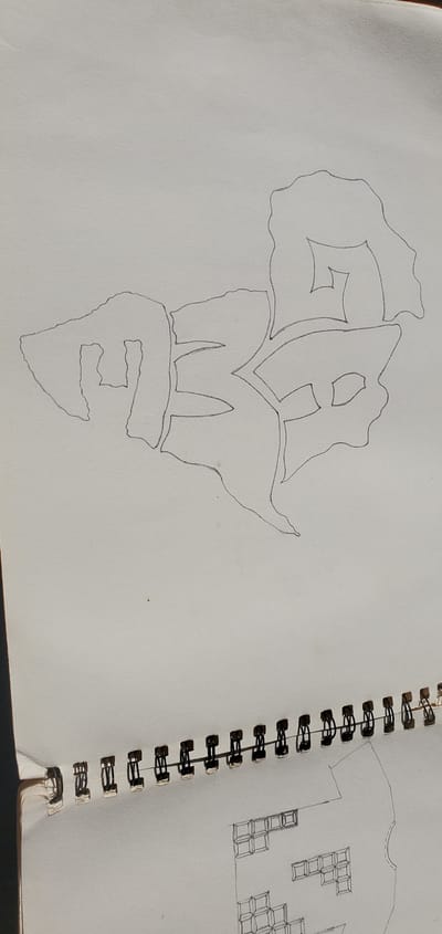 A sketch of graffiti art in a notebook. The graffiti appears to be made of blocky, stylized letters. The image shows the top portion of a spiral-bound notebook. The notebook paper is white and appears to be slightly textured. The graffiti is drawn in black pencil and has a thick outline. The lower portion of the image shows the spiral binding of the notebook and the beginning of another sketch, which appears to be a floor plan or architectural drawing. There are no people visible in the image. The lighting suggests the notebook is placed in an area with natural light. There is no information within the image to suggest a location in Goni Gara, Nigeria.