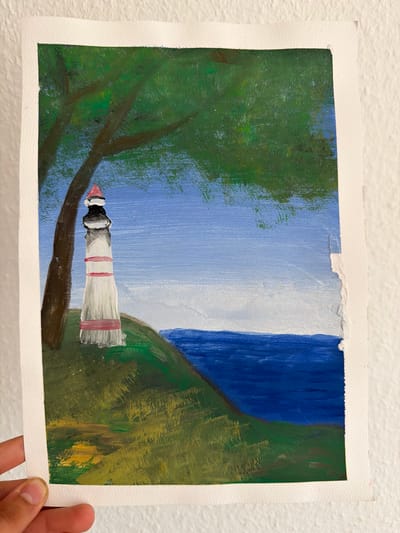 This is a painting of a lighthouse on a grassy hill overlooking the sea. The lighthouse is white with red bands and a red roof. A tree with green leaves is next to the lighthouse. The sky is blue with some white clouds. The sea is dark blue. The painting is on paper and is held by a person's hand. The background is a textured white wall. The location in the city of Nienburg/Weser, Germany is not depicted or implied by the image.