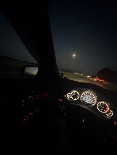 The image captures the interior of a car driving at night, likely on a highway. The dashboard lights are illuminated, showing various gauges and controls. The main speedometer displays a speed of 100 km/h, and the engine temperature is 95°C. The gear selector is in the "P" (Park) position. Outside the car, the road is visible with other vehicles' headlights in the distance. A faint moon or light source is visible in the dark sky. The location is stated to be the city of Krivina, Bulgaria.