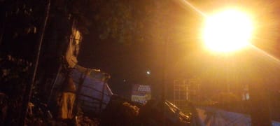 At night, a bright light illuminates a scene in Ndenderu Ward, Kenya. A sign reading "ROYAL BRAINS SCHOOL" is visible. There appears to be a structure with a cage-like frame and debris in the foreground. The scene is dark and difficult to discern clearly.