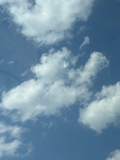 The image shows a blue sky with scattered white clouds. A faint arc, possibly a rainbow or optical illusion, is visible in the upper left quadrant of the image, super-imposed on the clouds. The sky appears clear and bright. There are no people, buildings, or any other identifiable objects present in the image. The scene is a natural outdoor environment. There is no specific information about the location in Parvenets, Bulgaria.