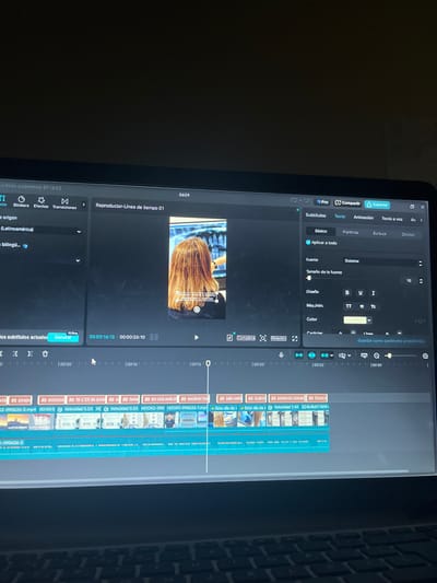 The image shows a close-up view of a laptop screen displaying a video editing software interface. The software appears to be CapCut, indicated by the "Pro", "Exportar", and "Compartir" buttons. The main part of the screen shows a video timeline with several clips and audio tracks. The video preview window displays a woman's back, with her hair styled and a digital image of teeth visible in the background, suggesting the video is related to dentistry or dental aesthetics.
On the right side of the screen, there are editing panels for "Subtítulos" (Subtitles), "Texto" (Text), "Animación" (Animation), and "Texto a voz" (Text to speech). The "Texto" panel is open, showing options for font, size, design, and color.
The timeline indicates the current playback position is around 00:26:10. Below the timeline, there are several clips with file names like "2-090626-3.mp4", "HOOK2-090", and "HOOK1-090626-1.mp4".
The interface is in Spanish. The top bar shows "Guardado automático: 07:18:03" (Automatic save: 07:18:03). There is no discernible information or visual cue within the image that places the scene in San Luis, Peru, or any other specific city. The context is purely digital, within the confines of the video editing software on the laptop.