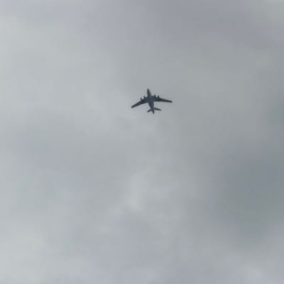 The image shows an airplane flying in a cloudy sky. The airplane is silhouetted against the overcast sky, and its details are not clearly visible. It appears to be a large jet with four engines. The airplane is flying at a high altitude, and there are no visible people or ground features. The weather appears to be overcast, with no clear indication of the time of day. The scene is a common one for aviation photography, capturing an aircraft in flight. No text is visible in the image.