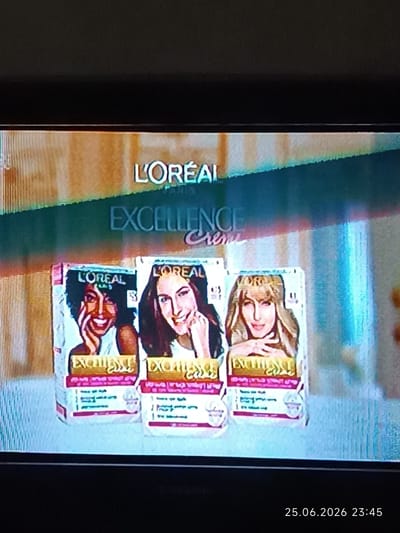 The media file displays a television screen showing an advertisement for L'Oréal Excellence hair dye. Three boxes of the product are prominently featured, each with a picture of a woman on the front, representing different hair colors and skin tones. The L'Oréal Paris logo and "Excellence Creme" text are visible at the top of the display. The image is likely a still from a television broadcast, given the timestamp "25.06.2026 23:45" in the lower right corner, suggesting it was recorded at that time in Bolhrad, Ukraine. The advertisement appears to be for hair coloring products and focuses on showcasing the results on different individuals. The overall tone of the ad seems positive and aspirational, as the women depicted have smiles on their faces.