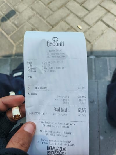 A hand, presumably belonging to a customer, holds a receipt from a restaurant named "Gacuan" in Bojongsoang, Indonesia, located at -6.971 latitude and 107.637 longitude. The receipt shows a purchase of 5 items of "Mie Gacuan," with a subtotal of 70,455. The receipt details a discount of 10,920, a PB1 of 7,045, and a grand total of 66,572. The date of the purchase is 25-04-2023 at 12:40. The transaction was made through ShopeeFood with self-order. The receipt also includes a QR code for customer feedback. The environment is outdoors, featuring a paved surface with brick-like pavers. A shadow from a person or object can be seen on the paved area.