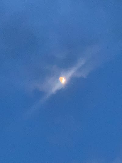 The image shows a yellow object in a clear blue sky with thin, wispy clouds surrounding it. The object appears to be spherical or slightly elongated. The photo was taken outside. Without additional information or context, it is not possible to determine the exact location in Boulder, Colorado.
