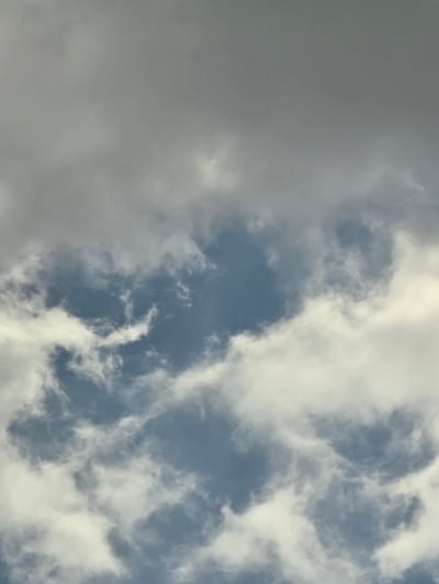 A cloudy sky is depicted in this image. The clouds are varied in density and color, ranging from dark gray to bright white, with patches of blue sky visible in between. The lighting suggests it might be daytime, possibly overcast or approaching a storm. There are no people, subjects, objects, actions, or interactions visible in the frame. The image is a close-up shot of the sky, implying it was taken from ground level or a low altitude. The location in Vasiliki, Greece is inferred from the provided context, not visually present in the image itself.