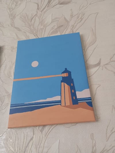 A rectangular canvas painting is displayed resting against a wall. The artwork depicts a minimalist, flat-color coastal landscape. The upper two-thirds of the canvas feature a light blue sky with a pale circular object in the upper left quadrant. A stylized lighthouse, rendered in dark blue with tan elements, is positioned on the right side, rising from a broad tan landmass or beach. A horizontal beam of light, depicted as a tan rectangular shape, projects from the lighthouse. A dark blue body of water with several light-colored horizontal wave lines separates the tan landmass from the horizon. The wall against which the painting rests is covered with light-toned, textured wallpaper featuring a repeating pattern of subtle, stylized botanical motifs. No individuals are present. The image was captured indoors in the city of Яромаска, Russia.