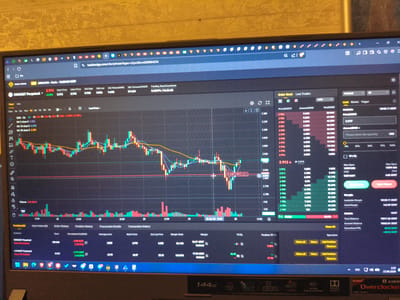 The image displays a cryptocurrency trading platform interface on a laptop screen. The platform shows a chart for "UNIUSDT Perpetual," indicating trading activity. Key elements visible include:
* **Trading Chart:** A candlestick chart showing price movements over time, with various technical indicators like moving averages plotted on it.
* **Order Book:** A section displaying buy and sell orders with associated prices and volumes.
* **Last Trades:** A log of recent executed trades.
* **Position Information:** Details of open positions, including contract, quantity, unrealized PNL, average price, and mark price.
* **Trading Controls:** Buttons for placing buy and sell orders, as well as managing existing positions.
* **Account Balances:** Information on available margin, total balance, account balance, and unrealized PNL.
* **Browser Tabs:** Several browser tabs are open at the top of the screen, including one for the trading platform itself.
* **System Tray Icons:** Icons for various applications and system functions are visible in the bottom right corner of the screen.
* **Laptop Details:** The bottom bezel of the laptop displays "144Hz," "Ryzen," and "Overclocked," indicating the laptop's specifications.
The image is taken from an angle, suggesting the laptop is placed on a surface within a room. The background shows a textured yellow wall, possibly wallpapered. There are no people or direct interactions visible in the image. The scene depicts a digital trading environment. The location of Rubtsovsk, Russia, is not determinable from the image content.