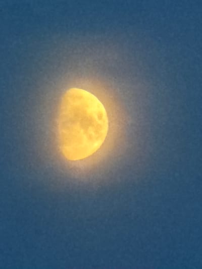 A waning crescent moon is visible in the night sky over Kuseevo, Russia. The moon is illuminated from the right, casting a soft glow. The sky is a deep blue. There are no people or man-made objects visible in the image.