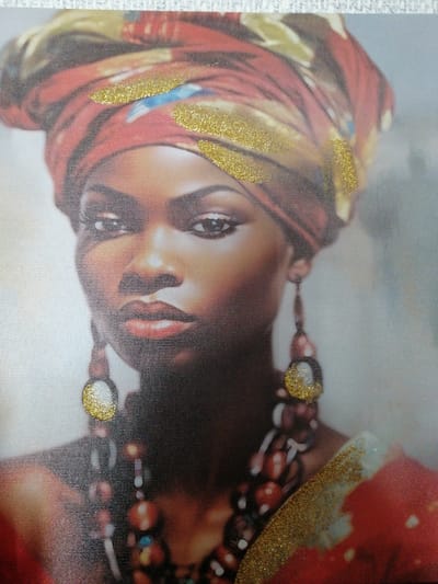 A close-up, head-and-shoulders portrait depicts a Black woman wearing a red and gold headwrap adorned with gold glitter accents. She has large, dangling earrings, one of which is visible and also features gold glitter. A beaded necklace is visible around her neck. The background is softly blurred with a light grey and white gradient. The image is a photograph or print with visible texture, likely from the material it is printed on. There is no discernible urban environment or location in Zhabinka, Belarus.