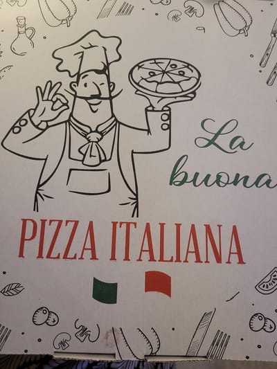 This media file presents a top-down view of a pizza box lid, featuring a vibrant Italian-themed illustration. The central figure is a black-outlined, cartoon-style chef, depicted wearing a traditional chef's hat and uniform. The chef holds a round, sliced pizza on a peel with one hand, while the other hand forms an "ok" gesture, conveying quality or deliciousness. A friendly smile is visible on the chef's face.

The light, possibly off-white, surface of the pizza box is adorned with line-art illustrations of various pizza ingredients and kitchen items. These include bell peppers, mushrooms, olives, sliced tomatoes, an oil cruet, and cutlery (a fork and knife).

Vertical text is a prominent feature on the right side of the box. "La buona" is written in an elegant green script font, translating to "The good" in Italian. Below this, "PIZZA ITALIANA" is displayed in bold, red, sans-serif capital letters. Further down, two solid rectangular blocks of color, one red and one green, are visible, unmistakably representing the colors of the Italian flag when combined with the box's light background.

The overall design is clean, utilizing line art against a light background, enhancing the aesthetic appeal. The image is captured at a slight angle, causing the vertical text and chef illustration to appear diagonally oriented. The illustration and text strongly emphasize an authentic Italian culinary experience. Given the location context of Sogliano Cavour, Italy, this further reinforces the genuine Italian origin of the pizza.