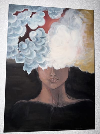 This is a painting of a woman's head and shoulders against a dark background. The woman's face is partially obscured by abstract, cloud-like forms in shades of white, light blue, and yellow, with hints of red and gold. The clouds appear to be emanating from or covering her head. Her skin tone is a medium brown, and her lips are painted a subtle pink. She is wearing a dark, possibly black, garment that covers her shoulders and chest. The background is predominantly black, with some textured white areas visible on the right and top edges of the canvas. The painting is displayed on a white, textured wall. There is no discernible information about the city of Giengen an der Brenz, Germany within the image itself.