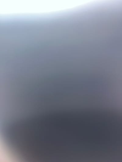 The image displays an extremely blurred and out-of-focus field of color, primarily a gradient. The upper portion is a very light gray or white, transitioning downwards into a darker gray with subtle blue or purple undertones. No discernible subjects, objects, people, actions, or interactions are visible. The environment cannot be identified from the image content. The image provides no visual information to confirm or determine a specific location within the city of Choctaw, United States.