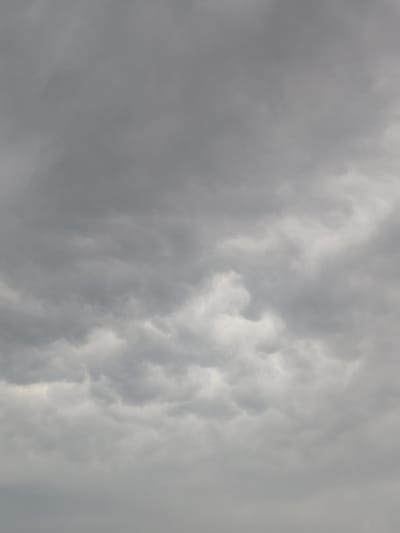 The image shows a cloudy sky over Skurygino, Russia. The clouds are dark and gray, indicating overcast conditions. There are no visible people, subjects, or objects in the frame, just the atmospheric conditions. The environment is solely the sky above the city.