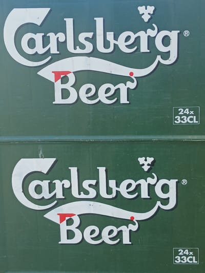 The image shows two unopened 24-can packs of Carlsberg beer, each containing 33CL of beer. The packs are green with white lettering and logos. The label reads "Carlsberg Beer" with the Carlsberg logo above. The notation "24x 33CL" appears in the top right corner of each pack. The image suggests these packs are located in Sotira, Cyprus, although there is no distinct location visible.