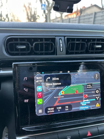 The image shows a car's dashboard with a navigation screen displaying a route. The estimated arrival time is 18:00, with 75 km to go and an estimated travel time of 1 hour and 9 minutes. The current time is 16:51, and the car is currently on "2ème Avenue," 20 meters away from a turn. The temperature is 22 degrees Celsius. The navigation is displaying a route through "Chemin du Charbonnier," and "Rue du Lyonnais".  The phone has 5G and is showing multiple apps.