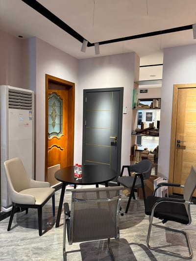 The image shows the interior of a building in Chancheng District, China. The interior includes two doors, one black and one wooden, along with an air conditioning unit installed on the wall. There are three chairs positioned near a table. The floor is tiled. The scene is generally well-lit.