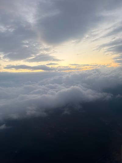 The image depicts a cloudy sky at what appears to be sunset, with a golden band of light breaking through the clouds. The clouds range in color from light grey to dark grey/black. The location is potentially Vecsés, Hungary based on the user's prompt. There is no sign of people, actions, or interactions visible within the frame. The environment is dominated by the atmospheric conditions.