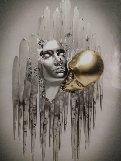 The image displays a close-up of a sculpture featuring two abstract heads. One head is metallic silver, with closed eyes and a neutral expression. The other head is a golden, skull-like form pressed against the silver head. The heads are positioned amidst what appear to be elongated, translucent, ice-like shards that form a backdrop and surround the figures. The lighting creates a dramatic effect, highlighting the reflective surfaces of the sculptures. The background is a soft, gradient grey. There is no indication of a specific location in Offenbach am Main, Germany.