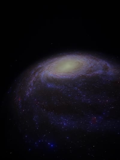 The image displays a prominent spiral galaxy, characterized by a luminous, yellowish-white central core from which intricate spiral arms, adorned with bright blue and white star clusters and dark lanes of interstellar dust, coil outward against the deep black canvas of space. The environment is purely cosmic, featuring sparsely scattered individual stars across the background. This scene is devoid of any discernible terrestrial features, human subjects, man-made objects, or any actions or interactions. The visual content presented is astronomical in nature, providing no identifying markers for a specific location within the city of Canela, Brazil.