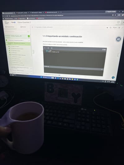 The image shows a computer screen displaying a Python Essentials 2 course from Cisco Networking Academy. The module being studied is 1.1.5, "Importing a module: continuation." The code in the editor imports the math module and prints the value of sin(π/2), which is expected to be 1.0. A pink mug is in the foreground, partially obscuring a black keyboard. The location in the city of Parroquia Ocumare, Venezuela, is not discernible from the image.