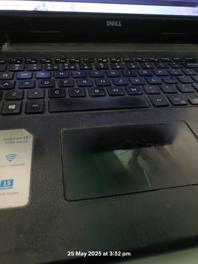 The image shows a Dell laptop computer with a black case. The keyboard and trackpad are visible. The laptop's screen is turned off. It is a Dell Inspiron 15 3000 Series. The laptop is on a surface with a date and time stamp on the lower right corner that reads "25 May 2025 at 3:32 pm." The image was taken in Dehradun, India.