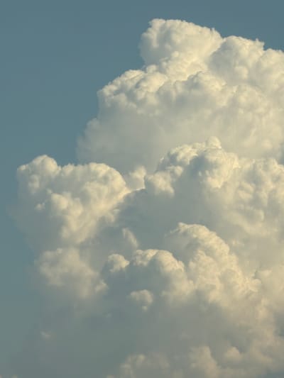 This media file depicts a dramatic sky filled with massive, billowing cumulus clouds. The clouds are predominantly white and puffy, with some areas showing darker, shadowed undersides, suggesting significant vertical development, possibly indicating cumulus congestus or cumulonimbus formations. The sheer scale and texture of the clouds dominate the frame, creating a sense of immense power and volume.

The background is a clear, pale blue sky, which provides a stark contrast to the dense cloud formations. There are no visible objects or people in the frame, focusing entirely on the natural phenomenon of the clouds. The lighting suggests it is daytime, likely mid-morning or afternoon, given the bright illumination of the cloud tops and the blue of the sky. The weather appears to be potentially turbulent or developing towards a storm, due to the impressive size of the clouds.

No text is visible in the image. The overall impression is one of natural grandeur and the dynamic forces of the atmosphere. The image captures a moment of raw, cloud-filled sky, likely taken from an outdoor vantage point.