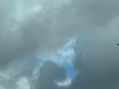 The image shows a cloudy sky with a patch of blue sky visible through a gap in the clouds. The clouds are dark and appear to be heavy with rain. There is no indication of human activity or any landmarks that would suggest a specific location within Volchikhinskii Maidan, Russia. The scene is entirely focused on the sky.