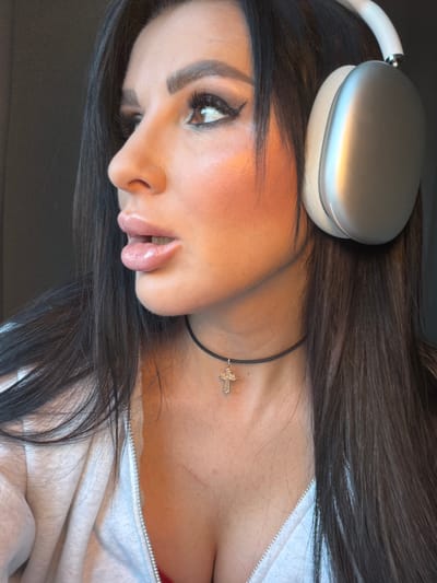 A close-up portrait of a woman. She is wearing headphones and a necklace with a cross pendant. The background is out of focus. There is no information to indicate the location is in Svkh Voronezhskiy, Russia.