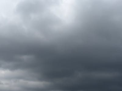 The image depicts a cloudy sky above Grapevine, United States of America. The clouds are predominantly dark gray and appear heavy, suggesting overcast conditions or impending rain. There are no visible people, subjects, objects, or actions. The environment is solely the sky.