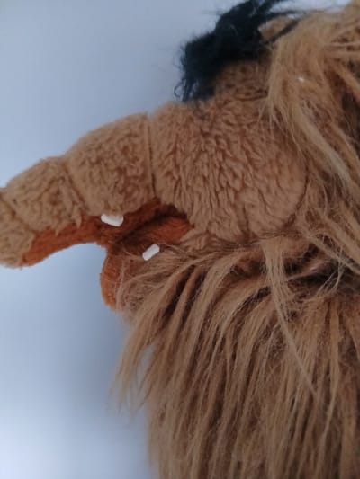This is a close-up, low-angle, indoor shot of a brown stuffed animal with black hair. The stuffed animal has a furry texture and appears to be part of a costume, possibly a headpiece. The background is a plain, light-colored wall. The image does not contain any information about the city of Vita-Poshtova, Ukraine.