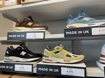 The image captures a retail display of New Balance 991 sneakers, showcasing four distinct colorways on shelves. The shoes are presented with accompanying signage indicating that they are "MADE IN UK" and priced at €175, with one discounted to €105. The sneakers are displayed in what appears to be a store setting, possibly a clothing or shoe store. The shoes are arranged with their respective price tags, making them easily visible to shoppers. The image gives the impression of a retail environment with a selection of New Balance 991 sneakers.
