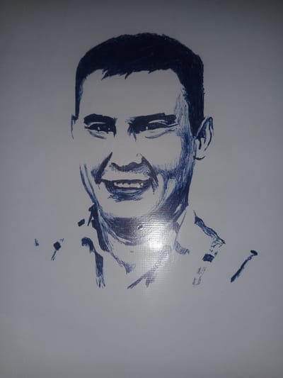 This is a pen and ink sketch of a man's head and shoulders, rendered in dark blue ink on a white background. The style is loose and impressionistic, with quick, energetic strokes that suggest form and shadow. The subject is looking directly at the viewer with a wide, open-mouthed smile, showing teeth. He has dark, short hair and appears to be wearing a collared shirt with some sort of patterned detail on the collar and shoulders. The sketch is framed by a slightly reflective surface, hinting that it might be under glass or plastic. The overall mood is cheerful and engaging, conveyed by the subject's broad smile and the lively quality of the drawing. There is no visible text in the image. The context of Gulbag, Uzbekistan, suggests the man might be a local resident.