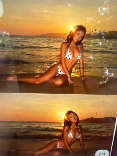 The image displays two photos of a young woman in a white bikini with black polka dots, posing on a beach at sunset. The sky is a vibrant orange and yellow, with the sun low on the horizon. The ocean waves are gently lapping the shore. The woman has long, dark hair, which is decorated with a flower in the top photo. She is wearing a necklace and bracelets. In the top photo, she is sitting with her legs tucked beneath her. In the bottom photo, she is lying on her side. The overall setting appears to be a tropical or coastal environment, with palm trees visible in the background of the top photo. The image is slightly blurry and has some light flares, suggesting it may be a photograph taken of a screen or a printed photograph. There is no indication of the city of Kara-Dıykan, Kyrgyzstan being present in this image.