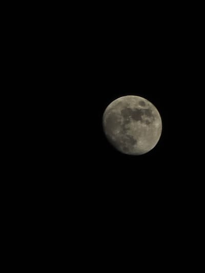 A medium shot depicts a partial moon, illuminated on its left side, set against a black, night sky. No other objects, people, or landscape features are visible. The image context does not provide any information relating to the location of Trachoni, Cyprus.