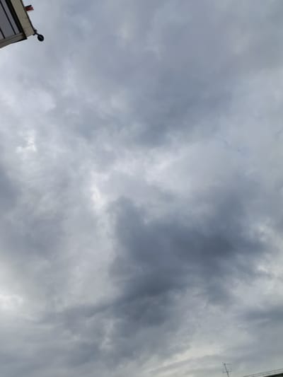 The image captures a cloudy sky from a low-angle perspective, looking upwards. The predominant feature is the overcast sky, filled with various shades of gray clouds. Some areas are lighter, suggesting diffused sunlight trying to break through, while other parts are darker and more dense. In the upper left corner, the edge of a building or structure is visible, with a small, dark circular object, possibly a security camera, attached to it. The building's edge appears to be a light color with some dark trim. Towards the bottom of the image, a portion of what looks like an antenna or a thin metal structure with horizontal elements is visible, possibly on a rooftop.
The weather appears to be overcast or on the verge of rain. The lighting suggests it is daytime, though the heavy cloud cover would obscure direct sunlight. The location cues, such as the type of building structure and the antenna, are generic enough not to pinpoint a specific type of setting within Novozybkov, Russia, but suggest an urban or semi-urban environment. There is no discernible activity taking place; the image focuses on the sky and a small part of the built environment. No text is visible in the image. The overall mood conveyed is somber or neutral, due to the cloudy sky and lack of vibrant elements.