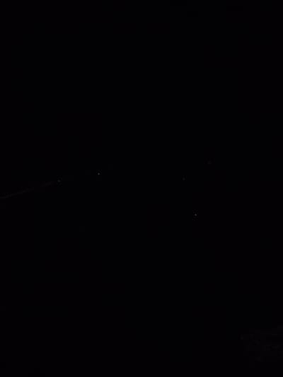 The image shows a dark or nighttime scene, possibly an outdoor location in Pintomakmur, Indonesia. There are a few faint points of light, which could be stars or distant lights. A thin, possibly linear feature is visible in the lower center portion of the frame. The scene is dark and lacks identifiable subjects or objects, and the environment is unclear due to the lack of light.