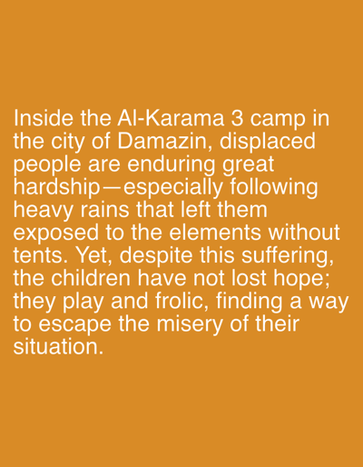 The image is a close-up, full frame shot of text on an orange background. The text is white and appears to be a caption or excerpt of a story. The text discusses the Al-Karama 3 camp in the city of Damazin, Sudan, where displaced people are enduring hardship, specifically from heavy rains that have left them exposed to the elements without tents. Despite the suffering, children in the camp are described as maintaining hope, playing and frolicking to escape their misery. The text is centered in the frame and appears to be well-lit. There are no people or objects visible in the image, only the text.